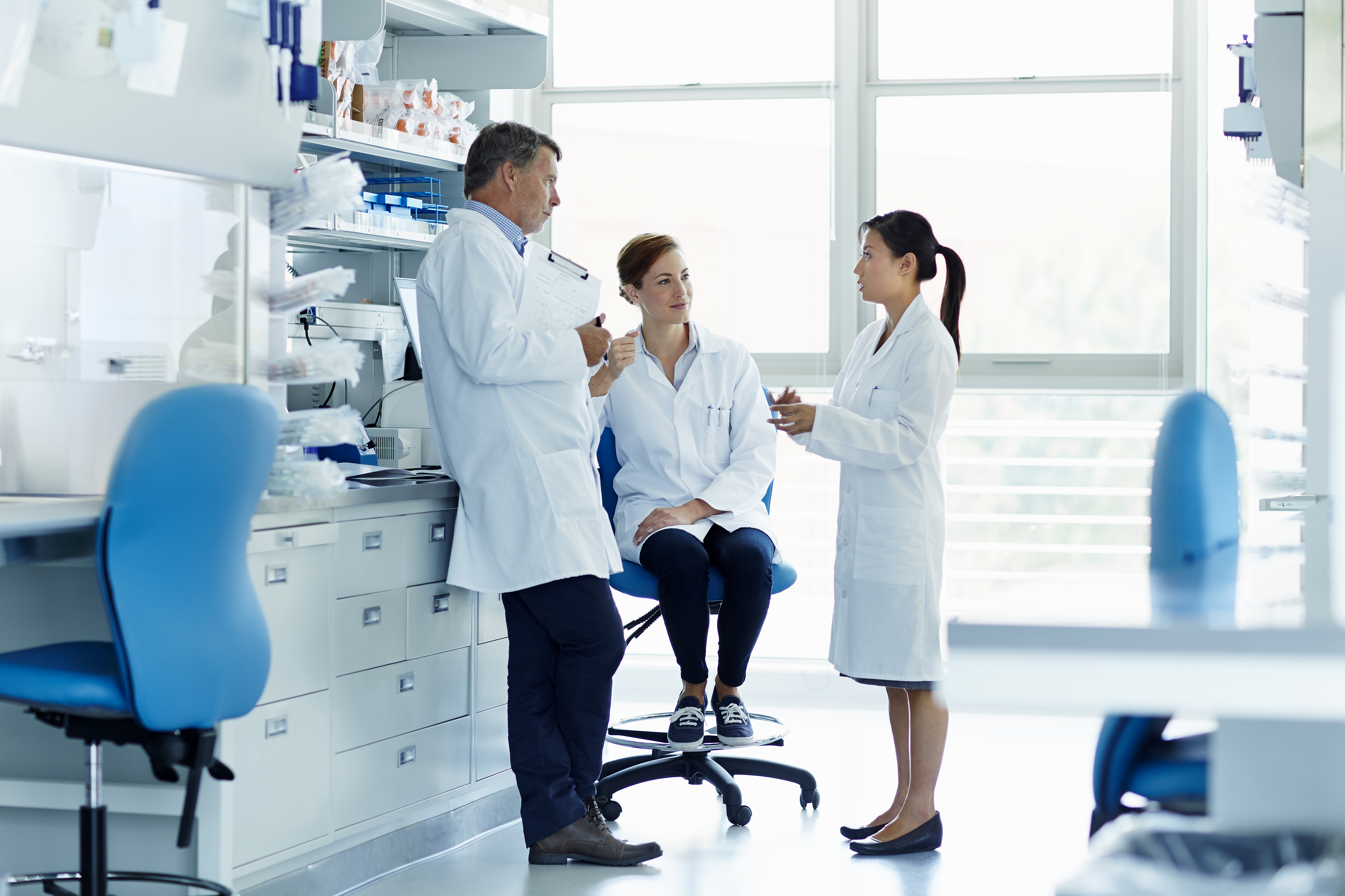 Three researchers in lab coats discussing a project in a laboratory