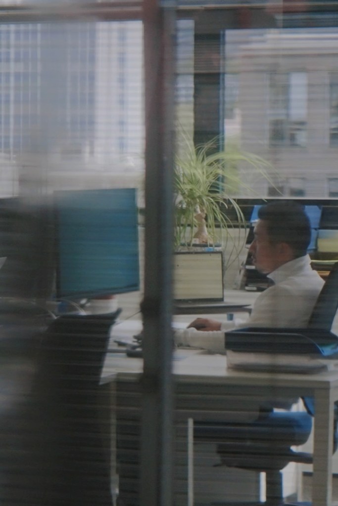 Person working at a desk with computer monitors in an office setting
