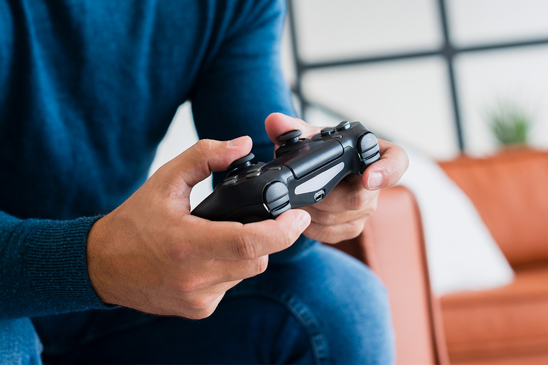 Close-up of a person holding a black video game controller at home