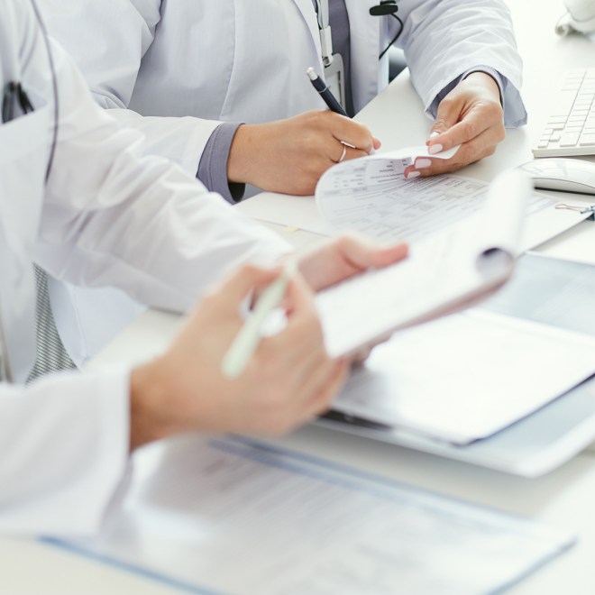 Two doctors reviewing paperwork at a desk