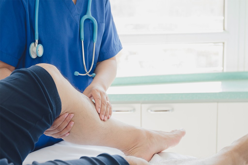 Healthcare professional examining a patient's leg in a clinical setting