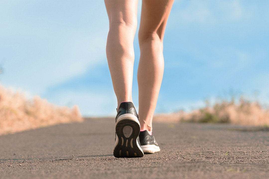 Person walking on a path, wearing black athletic shoes