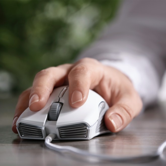Close-up of a hand using a white computer mouse on a wooden table