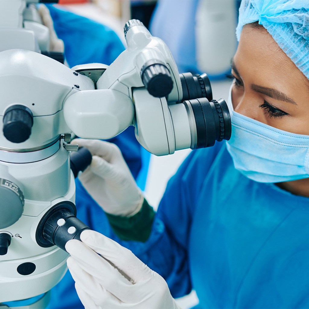 Ophthalmic surgeon adjusting a microscope in a medical setting